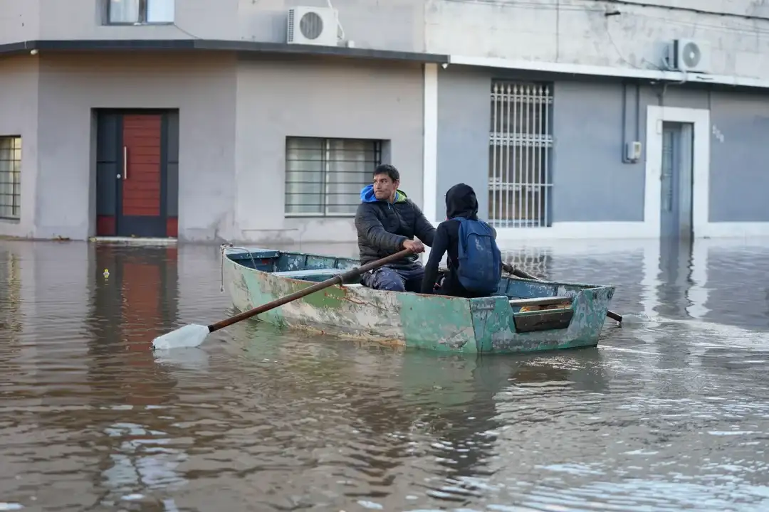 Imagen del 13 de mayo de 2024 de personas cruzando una calle inundada a bordo de un bote, en la ciudad de Paysandú