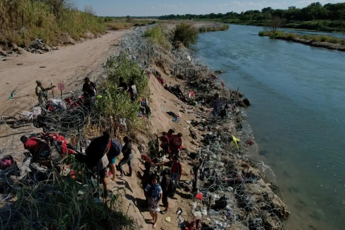 Miembros de la Guardia Nacional de Texas tratan de disuadir a los migrantes de trepar por el alambre de púas después de cruzar el Río Grande en Eagle Pass