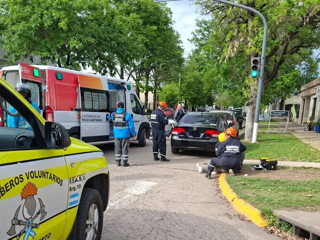 Personal de Bomberos Voluntarios y servicios de emergencia asisten a las víctimas tras el choque entre un auto y una moto en Eva Perón y Pringles.