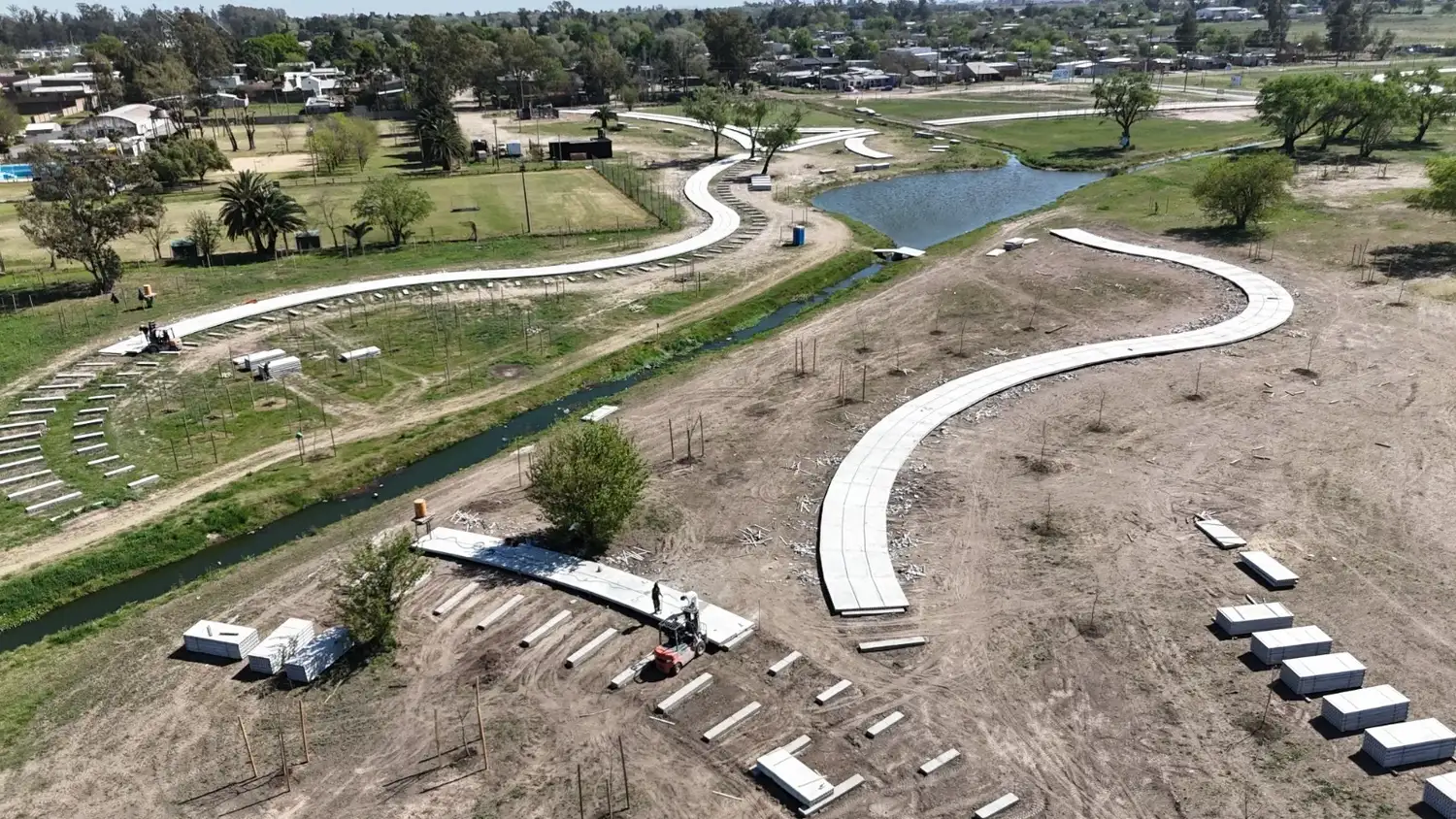 Vista aérea de las obras en el Área Recreativa Norte, donde se observa el avance en la construcción de senderos peatonales, el movimiento de suelo y la instalación de infraestructura junto al arroyo para este nuevo espacio público en la ciudad.