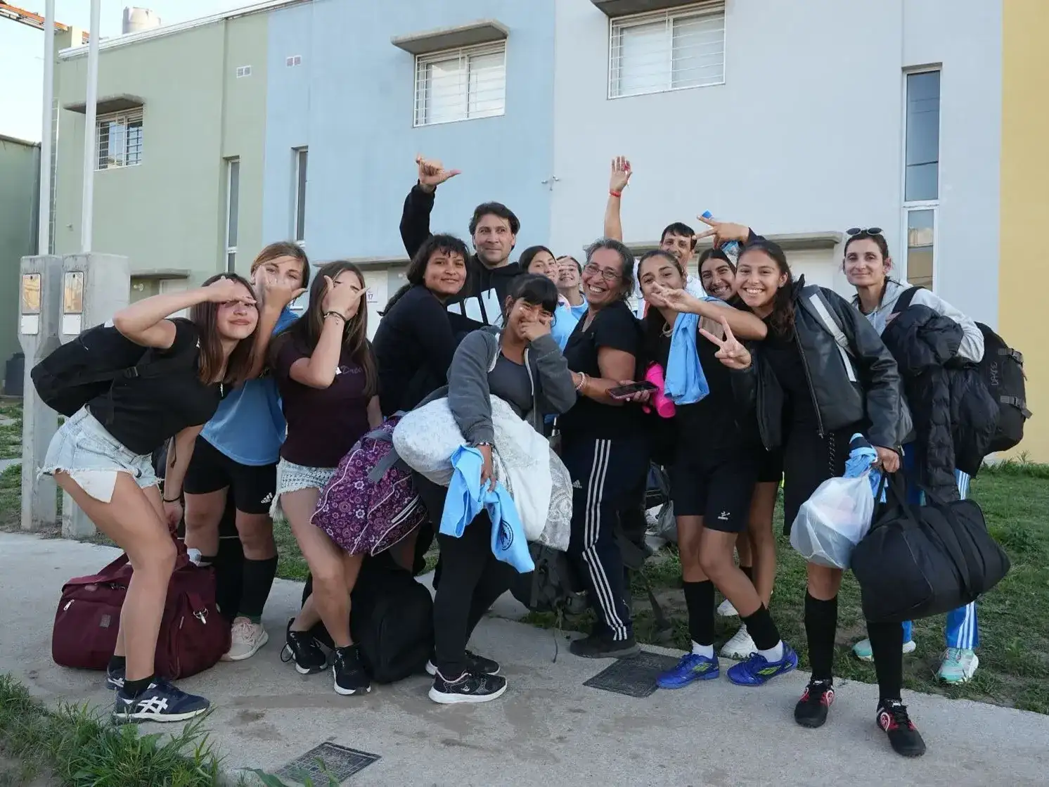 Un grupo de jóvenes deportistas y entrenadores posan sonrientes frente a los edificios de la Villa Suramericana en Santa Fe, celebrando su participación en este importante complejo habitacional destinado a atletas de toda la provincia.
