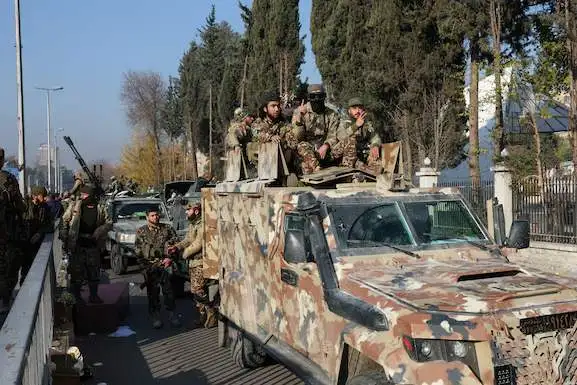 Combatientes rebeldes sentados en un vehículo, después de que tomaran la capital y derrocaran al dictador Bashar al-Assad, en Damasco, Siria
