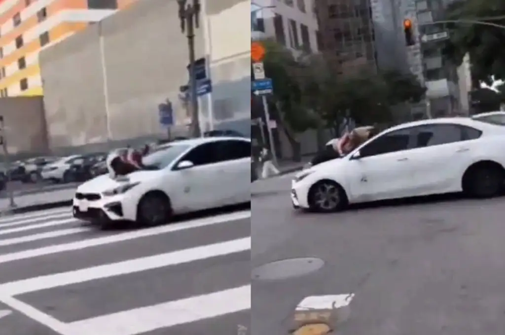 La mujer ferrada al capó de un auto
