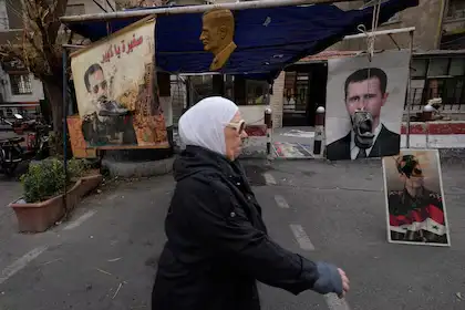 Zapatos colgados frente a retratos del depuesto presidente sirio Bashar Assad en Damasco, Siria, lunes 23 de diciembre de 2024.