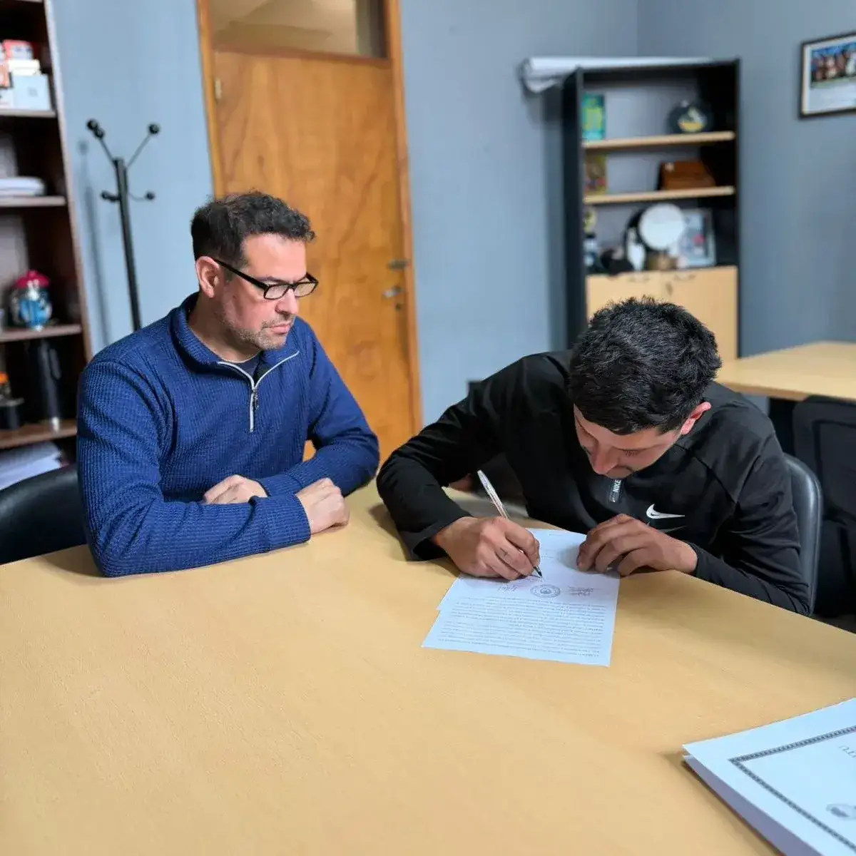 Kevin Ponce, el primer beneficiario, firmando junto al presidente comunal Cristian Vincenti.
